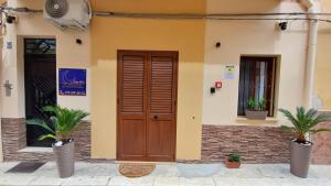a house with a wooden door and two potted plants at Sogni D'oro 01 in Partinico