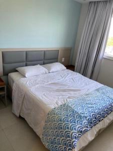 łóżko z niebiesko-białą kołdrą i oknem w obiekcie Apart Resort Aqualand Salinas w mieście Salinópolis