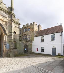 ein weißes Gebäude neben einem Gebäude mit einem Schloss in der Unterkunft Palace Garden Cottage in Bishop Auckland