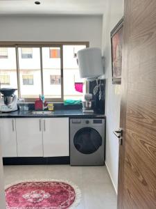 a kitchen with a stove and a sink and a dishwasher at Kénitra centre ville Mimosa in Kenitra