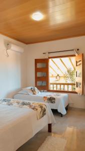 a bedroom with two beds and a window at Pousada encanto do mar, Nova caraiva-Ba in Porto Seguro