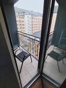 dwa krzesła na balkonie z widokiem na budynek w obiekcie Apartman 59 w mieście Zlatibor