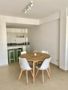 une salle à manger avec une table en bois et des chaises blanches dans l'établissement FIKA - Depto Temporario, à Puerto Madryn 20 autres photos