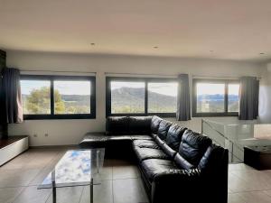 eine schwarze Ledercouch in einem Wohnzimmer mit Fenstern in der Unterkunft Casa Maju - Private pool with mountain views in Pals