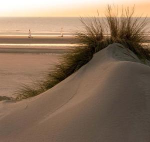 a sand dune with people walking on the beach at Val 1er in Quend-Plage