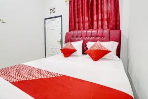 a bedroom with a red and white bed with red pillows at OYO 91886 Bfs Homestay Syariah in Jambi