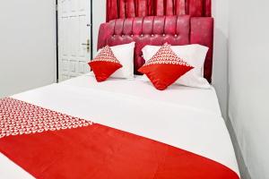 a red and white bed with red pillows on it at OYO 91886 Bfs Homestay Syariah in Jambi +20 photos