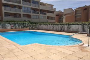 ein großer blauer Swimmingpool vor einem Gebäude in der Unterkunft Charmant cocon, vue mer, piscine et clim in La Seyne-sur-Mer