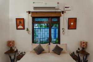 ヴァガトールにあるGOAROUND- Grand Chivar 1BHK Villa by Goaround Homes at Vagatorの窓と家具付きのベッドのある部屋