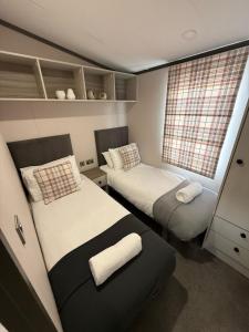 une petite chambre avec deux lits et une fenêtre dans l'établissement Grey Goose Lodge with hot tub at Brickyard Lakes, à Amotherby