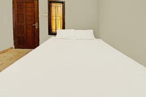 a white bed in a room with a door at Hotel O Diwi Homestay in Tjakranegara