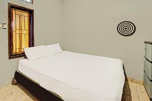 a white bed in a room with a window at Hotel O Diwi Homestay in Tjakranegara