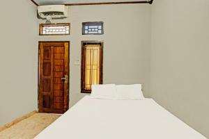 a bedroom with a white bed and two windows at Hotel O Diwi Homestay in Tjakranegara