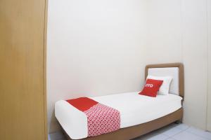 a bed in a room with a red pillow on it at Hotel O Kost Ketapang Syariah in Medan