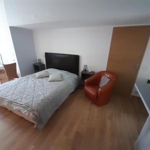 een slaapkamer met een bed en een stoel bij L'olivier TESSA Hôtesse suite 30m2 terrasse 20m2 in La Celle