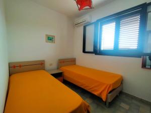 two beds in a room with orange sheets and a window at La Casa del Marinaio P1 in San Foca