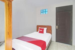 a bedroom with a bed with a red pillow on it at Hotel O Borneo in Manado