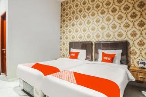 two beds with red pillows in a bedroom at SUPER OYO Capital O 92066 Papakoel Hotel & Cafe in Medan