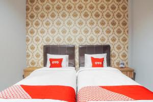 a bedroom with two beds with red pillows at SUPER OYO Capital O 92066 Papakoel Hotel & Cafe in Medan +25 photos