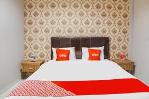 a bedroom with a bed with two red pillows at SUPER OYO Capital O 92066 Papakoel Hotel & Cafe in Medan