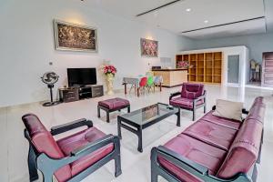 a living room with couches and chairs and a tv at OYO 92057 Reny Kost Syariah in Jambi