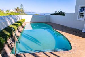 a blue swimming pool on a brick patio at Seaside Serenity: Tranquil Oceanview Retreat in Hermanus +21 photos