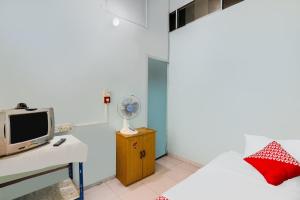 a bedroom with a bed and a desk with a fan at Hotel O Restu Ibu Homestay Syariah in Batu Ampar