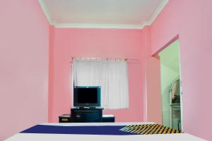 a bedroom with a pink wall and a television at OYO Life 92046 Garuda Residence in Palembang