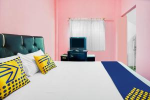 a bedroom with a large bed with a tv at OYO Life 92046 Garuda Residence in Palembang