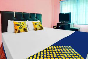 a bed with yellow and blue pillows and a television at OYO Life 92046 Garuda Residence in Palembang