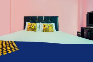 a bed with yellow and blue pillows on it at OYO Life 92046 Garuda Residence in Palembang