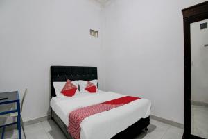a bedroom with a bed with red pillows on it at Hotel O Dinda Homestay Syariah in Dumai