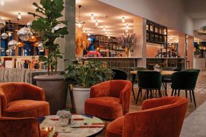 ein Restaurant mit orangefarbenen Stühlen, Tischen und Pflanzen in der Unterkunft Hotel Berlin, Berlin, a member of Radisson Individuals in Berlin