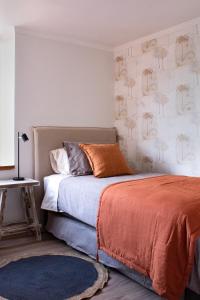 a bedroom with a bed with orange sheets and palm trees on the wall at Depto de lujo en Avenida Kennedy, cerca de Clinica Alemana in Santiago