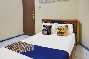 una camera con 2 letti con cuscini blu e gialli di OYO Life 92087 Griya Nurainy a Pasuruan