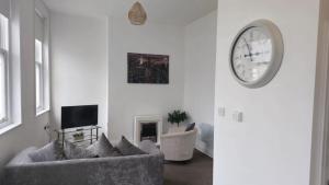 a living room with a couch and a clock on the wall at Irwell Chambers by L3 Apartments in Liverpool