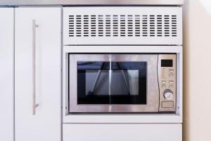 a microwave oven in a white cabinet at New Snug DoubleEnsuite in Central Forest Row in Forest Row