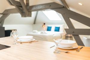a table with two glasses and a bed in a room at Nid douillet sous les combles in Châlons-en-Champagne