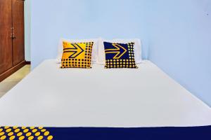 a white bed with yellow and blue pillows on it at Hotel O Kost Pak Suyatno Syariah in Ponorogo