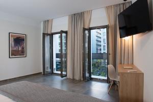 a hotel room with a desk with a television and windows at Evia Hotel in Athens