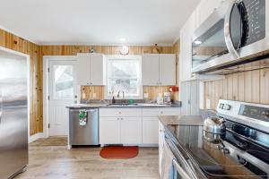 a kitchen with white cabinets and a stove top oven at Lobster Cove Retreat in Prospect Harbor