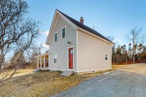 a white house with a red door on a road at Lobster Cove Retreat in Prospect Harbor