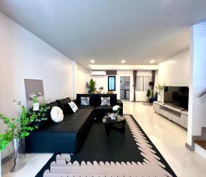 a living room with a black couch and a table at Chokchai village 9 in Nong Prue