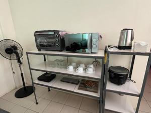 a television and a microwave on a shelf at NRD Staycation Transient House in Dasmariñas