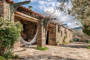 a stone house with a hammock outside of it at Casinha da horta in Mirandela