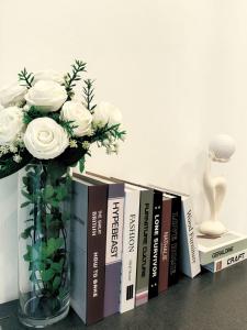 a vase with white roses and books on a shelf at Chokchai village 9 in Nong Prue