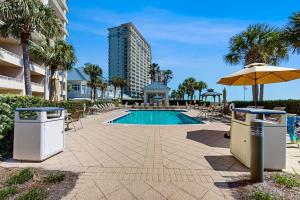 a swimming pool with an umbrella and two trash cans at Beach Club C502 in Gulf Highlands