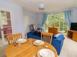 a dining room with a table and a blue couch at Nanny Jill's Cabin in Penrydd