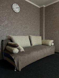 ein Sofa in einem Zimmer mit einer Uhr an der Wand in der Unterkunft Luxury apartment Slobozhansky Prospekt in Nizhnedneprovsk