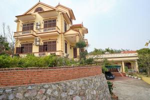 a large yellow house with a brick wall at Kim's Family Hotel in Ha Long